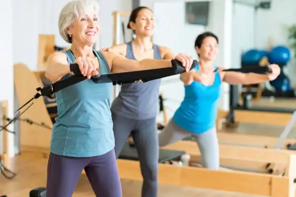 Toning Arms After 60: Empowering Womens Fitness Through Effective Weight Training 2 older woman doing weight training Hatfield and resistance in the gym to tone upper arms